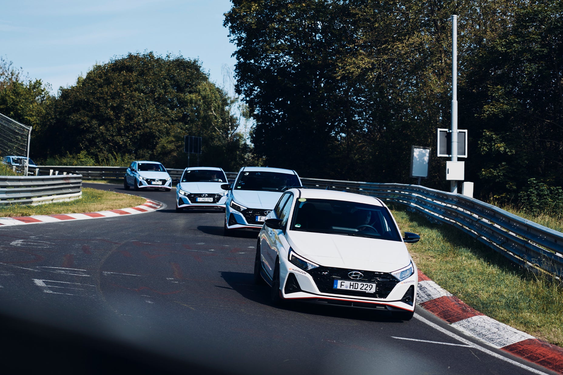 various Hyundai i20N cars driving on a racetrack
