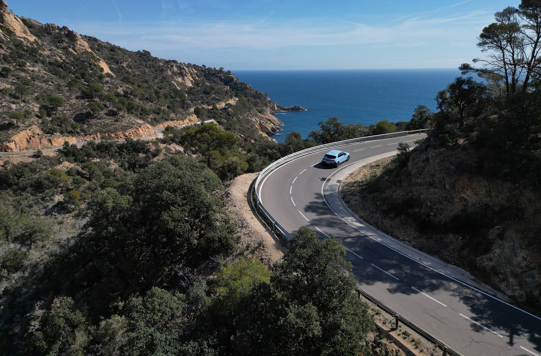 Hyundai IONIQ 5 N driving on a sunny coastal road from a distance
