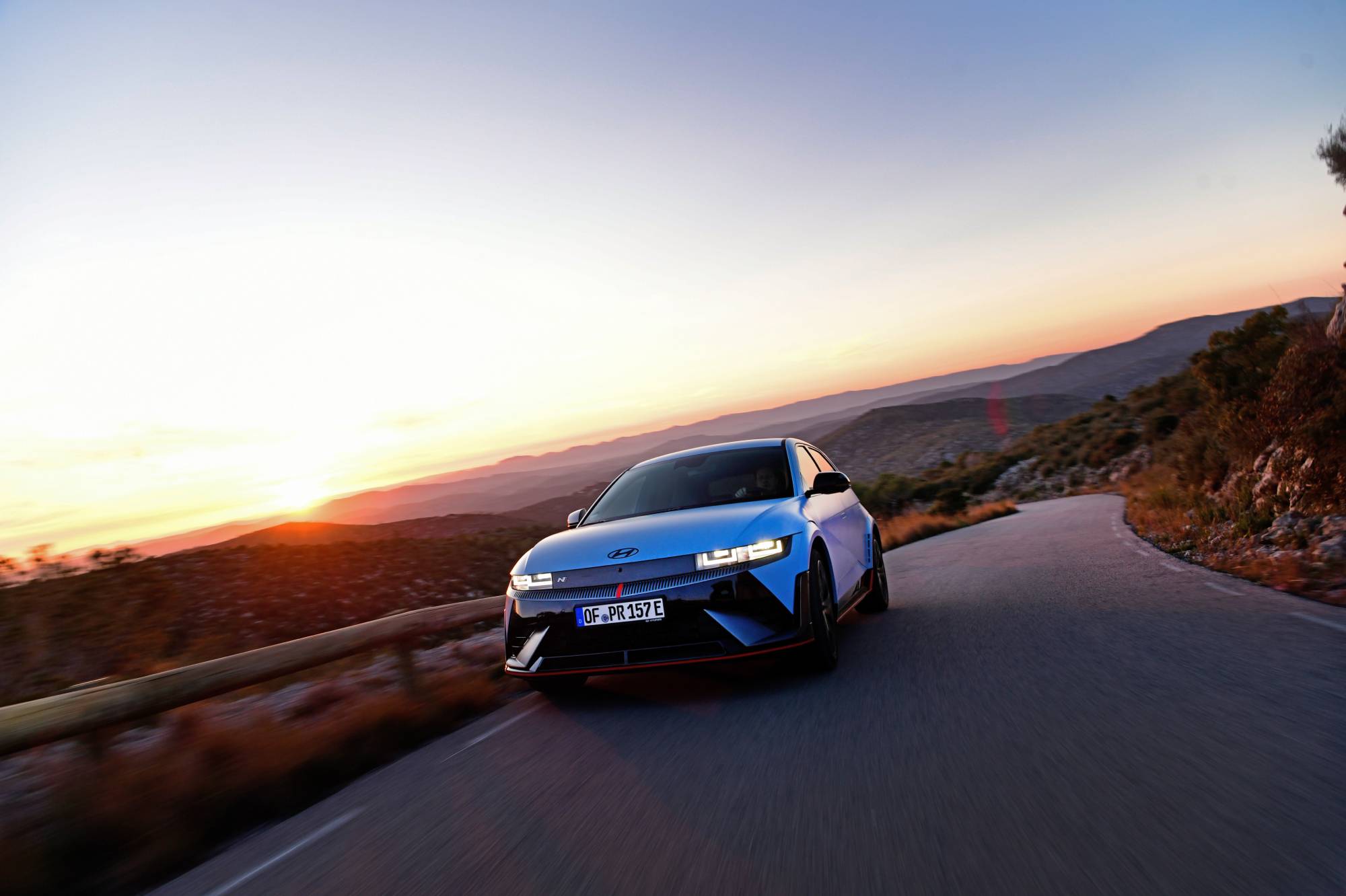 Hyundai IONIQ 5 N driving on a scenic road in the sunset
